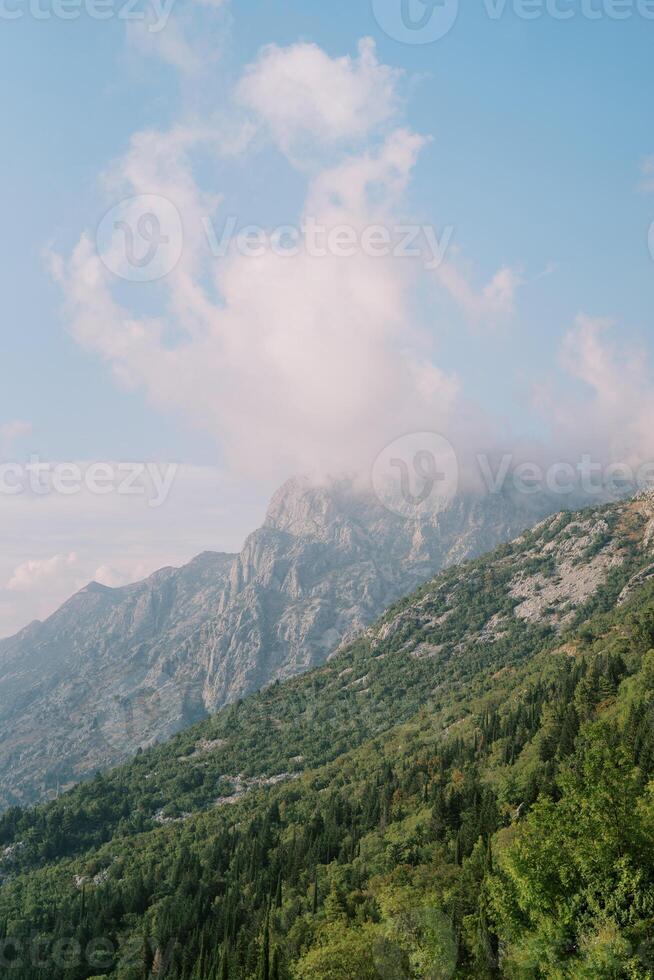 Fog over the peaks of a mountain range against a cloudy sky photo