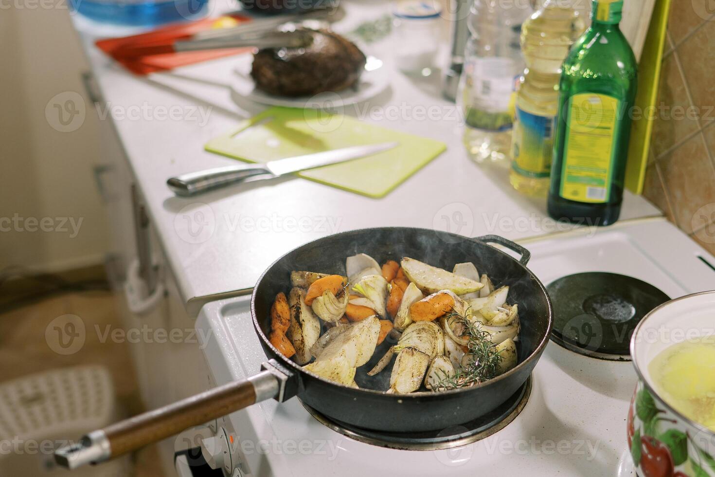 Sliced fresh vegetables are stewed in a frying pan on the stove photo