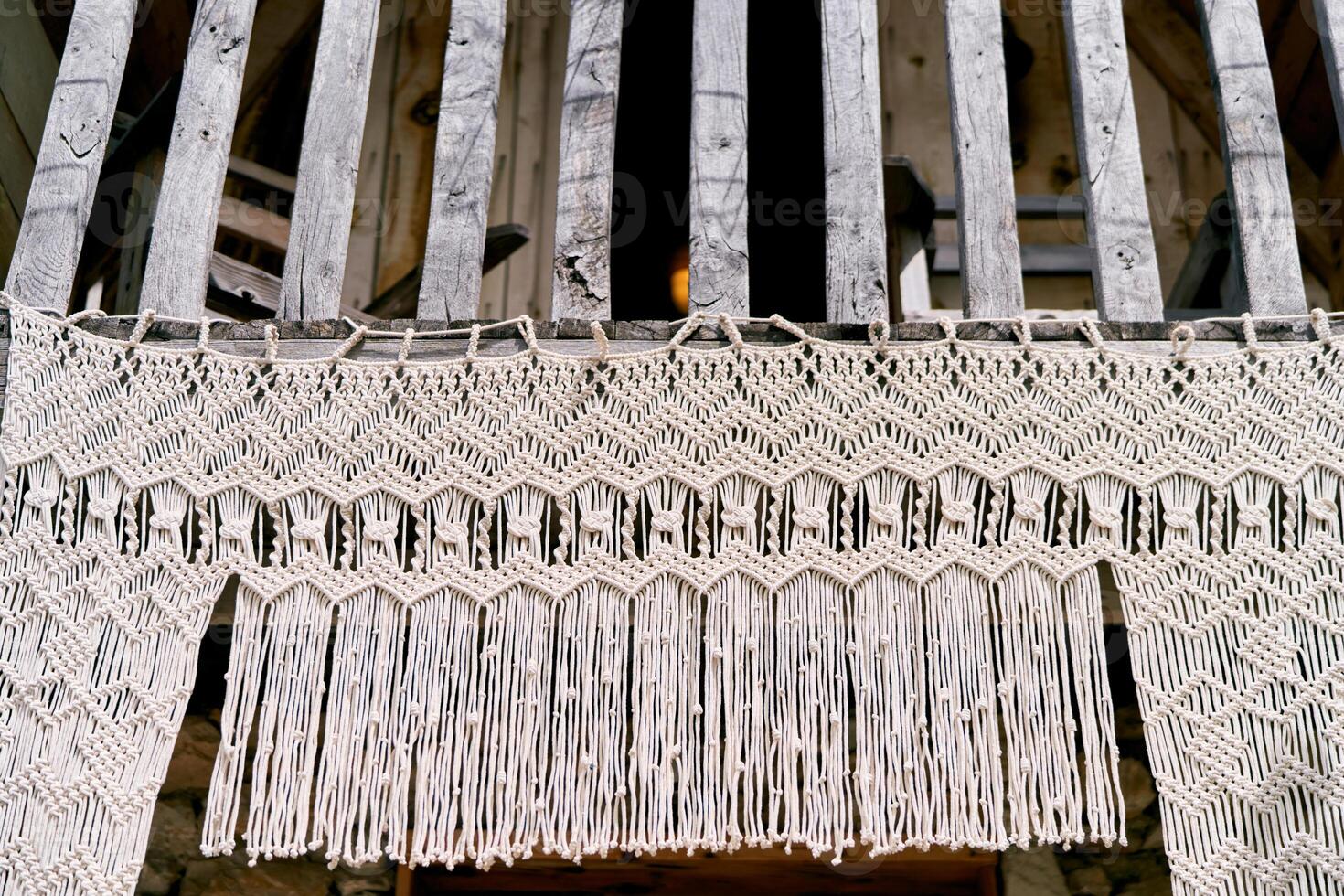 Macrame curtain hangs from a wooden canopy at a house photo