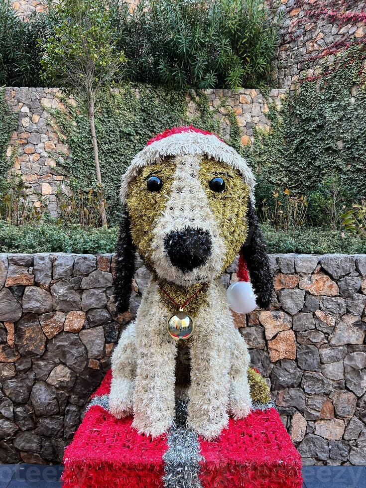 Fluffy Christmas figure of a dog in a Santa hat on a pedestal in the garden photo