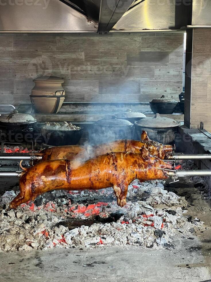 Roasting a Pig on a Spit, Cooking it Over a Charcoal Fire photo