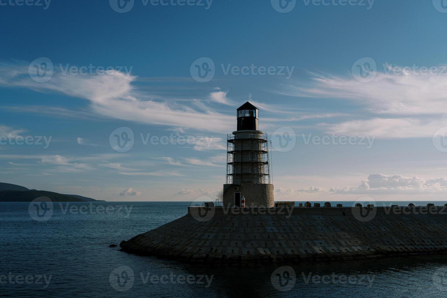 Lighthouse on a breakwater in the sea against the background of a twilight sky photo