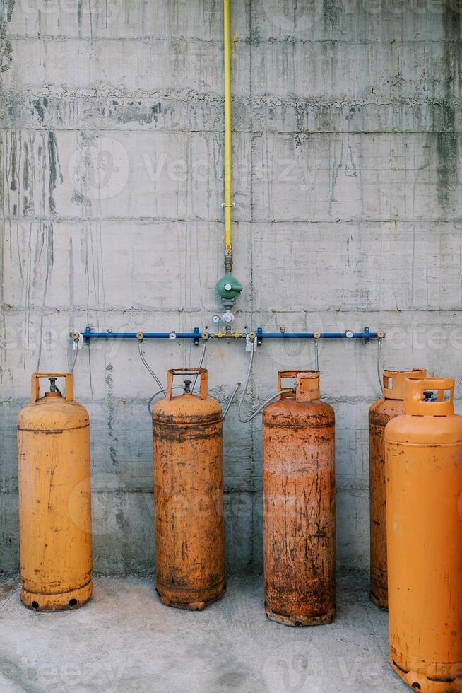Orange gas cylinders connected to pipes on a concrete wall photo