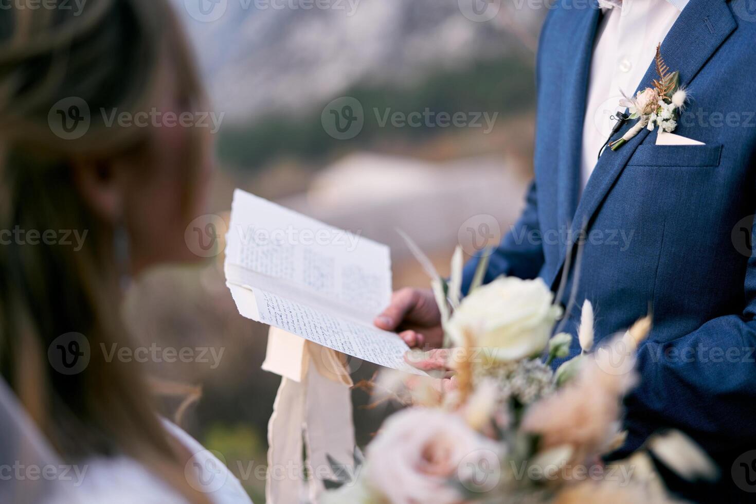 Groom reads the oath to the bride from a piece of paper photo