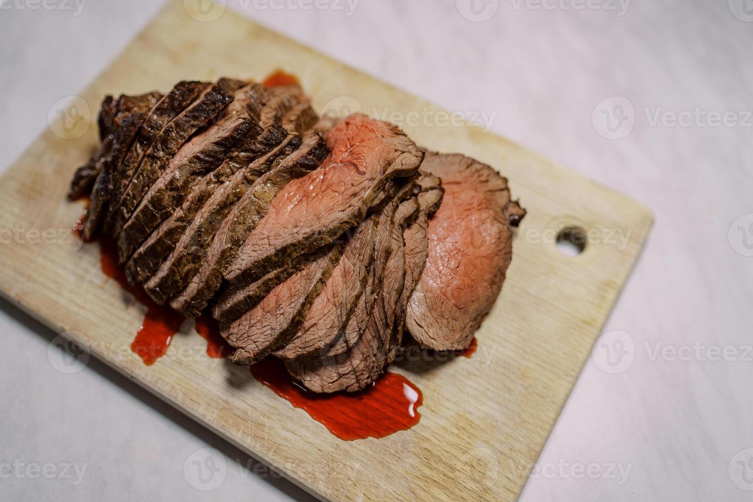 Roast beef slices with blood lie on a wooden cutting board on the table. Top view photo
