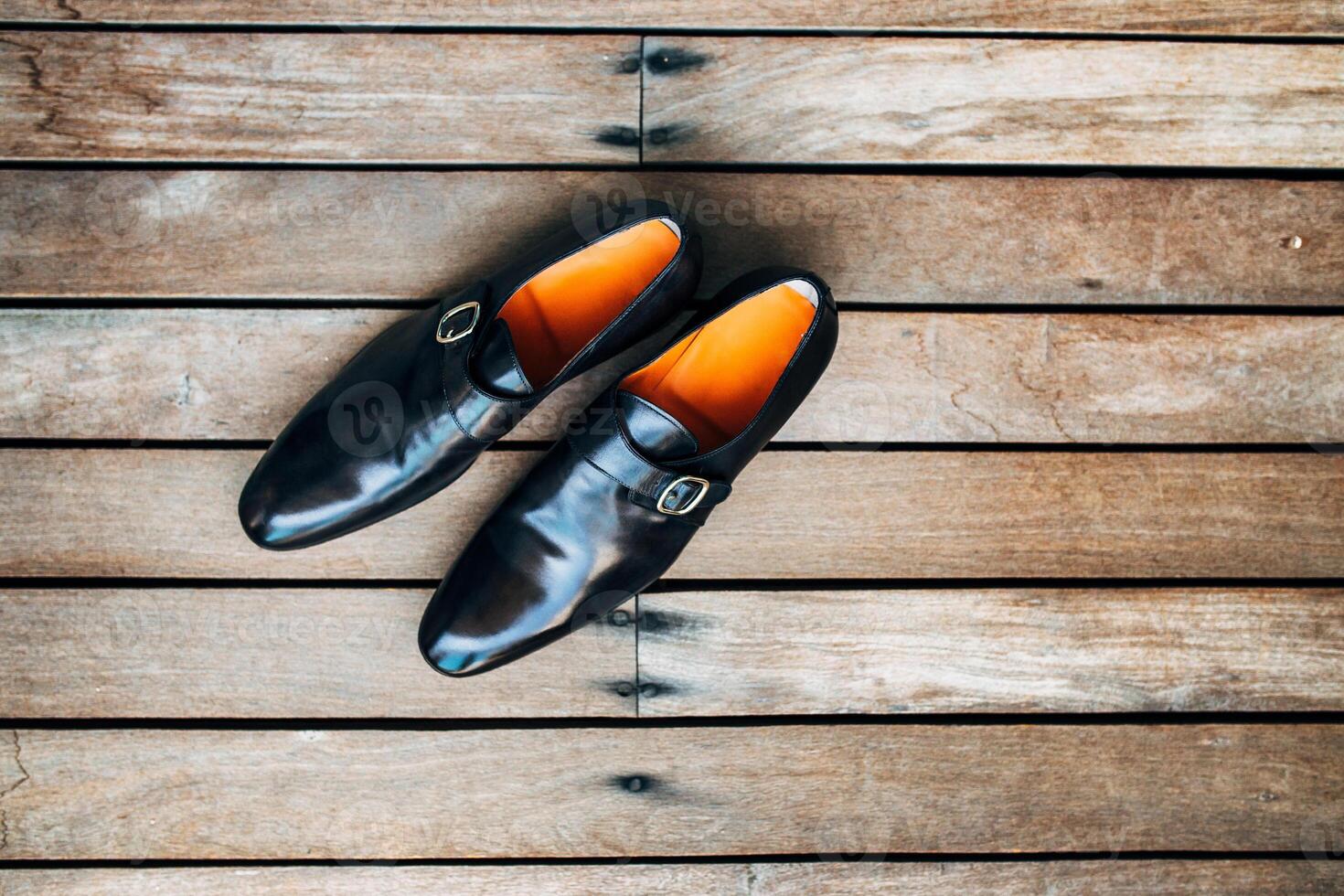 Stylish Black Leather Shoes with Orange Lining on Wooden Floor photo