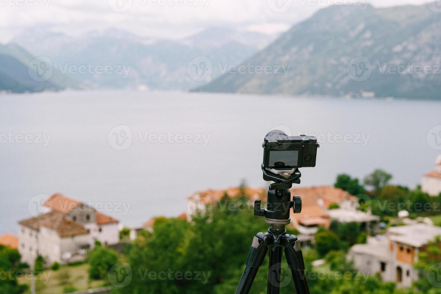 Camera on Tripod with Scenic View of Mountains and Water photo