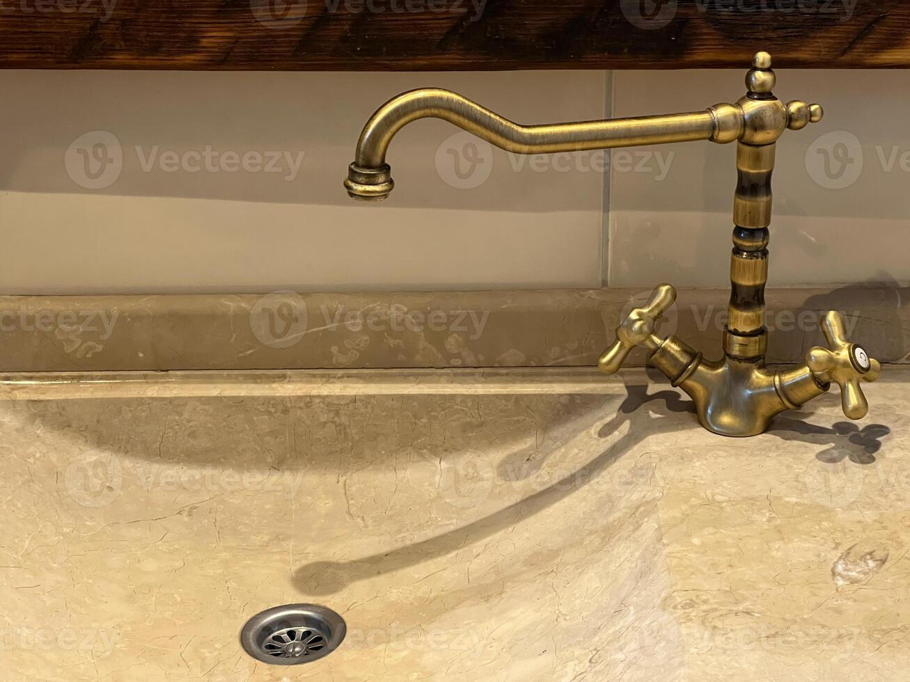 An Elegant Brass Faucet Design Beautifully Pairs with a Marble Sink photo