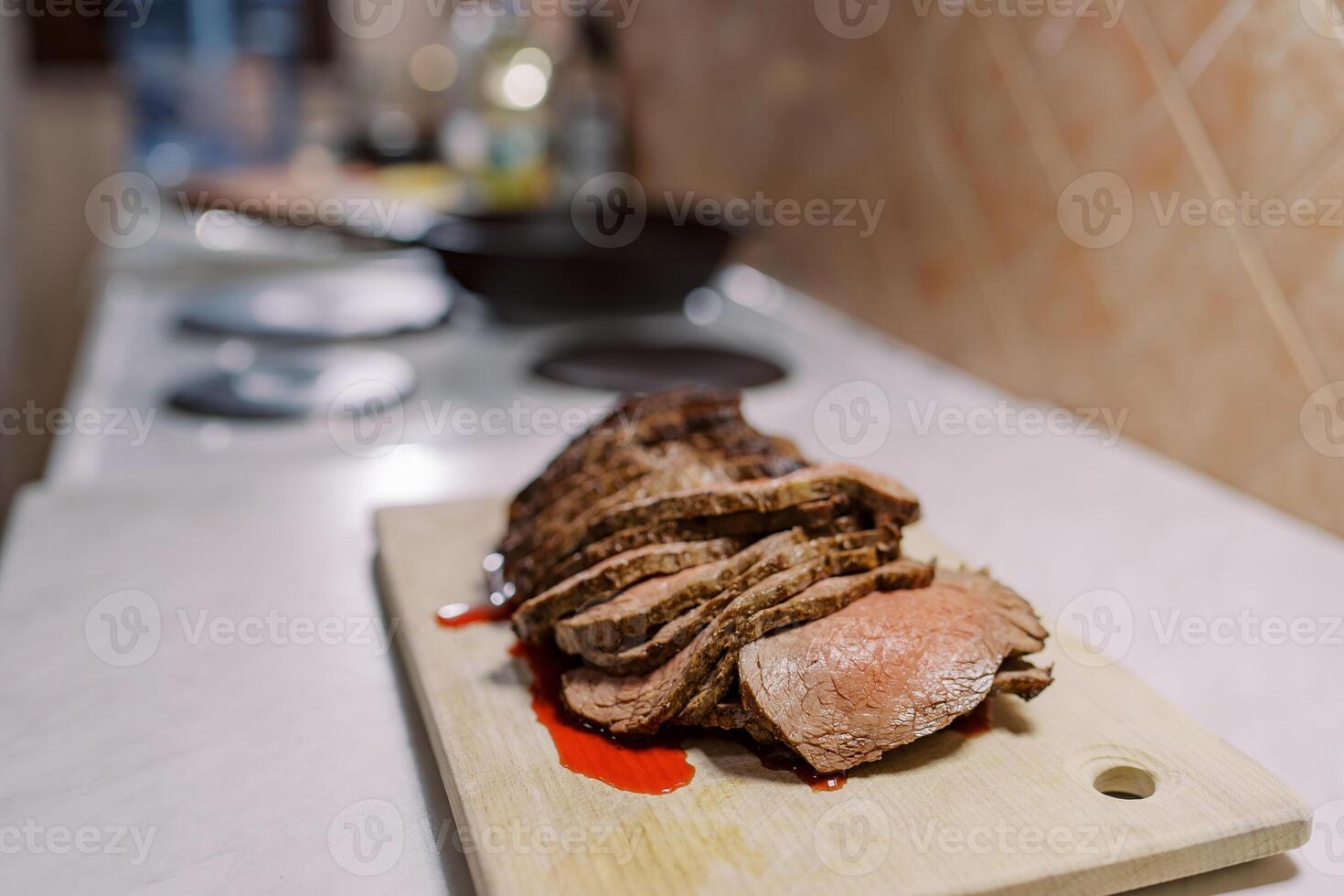 Sliced roast beef with blood lie on a wooden cutting board on the table photo