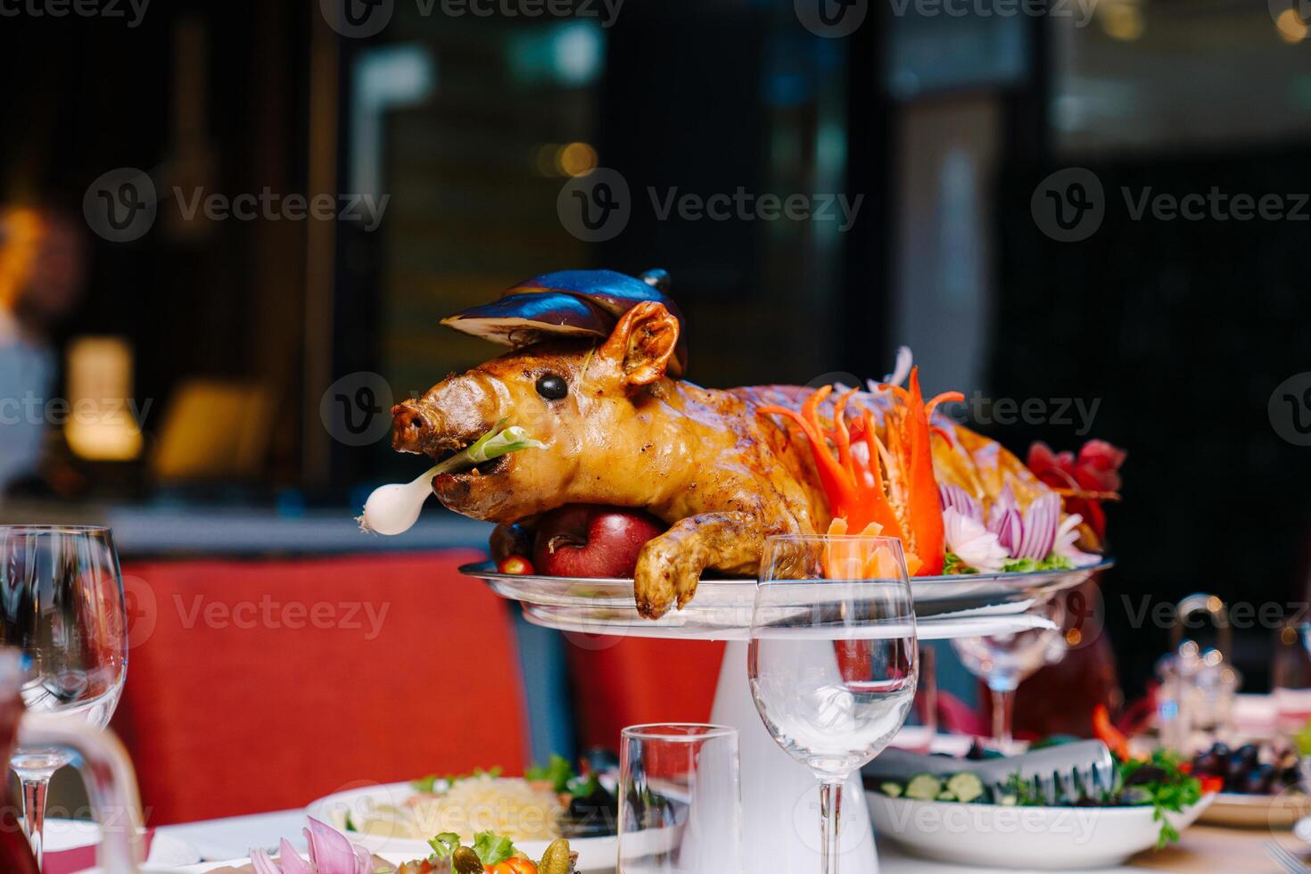 Roasted pig garnished with vegetables lies on a dish on a table in a restaurant photo