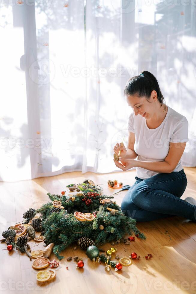 Smiling decorator paints a cone for a New Year wreath with a brush photo