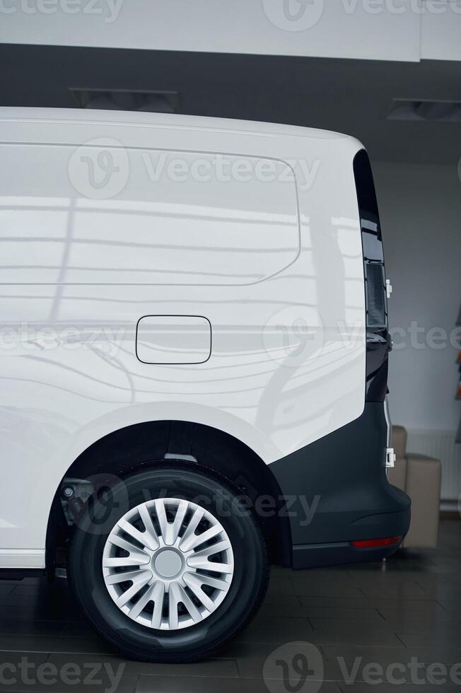 Side view of rear part of the white bus that is parked indoors photo