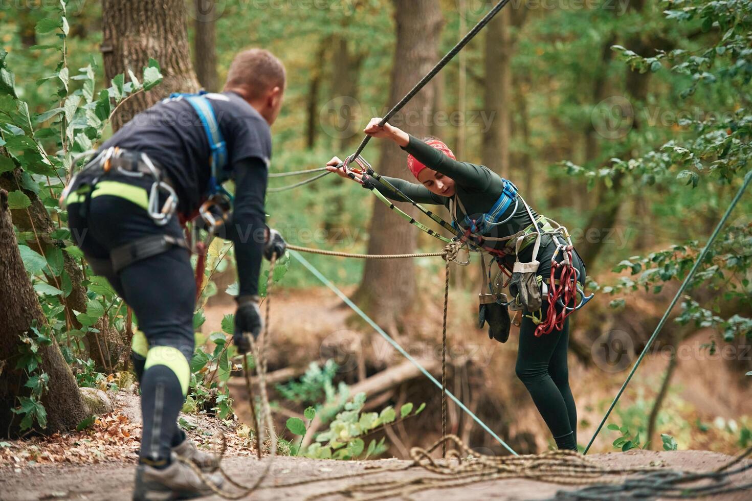 Preparing ,the, ropes. Man and, woman doing climbing in forest with use of safety equipment photo