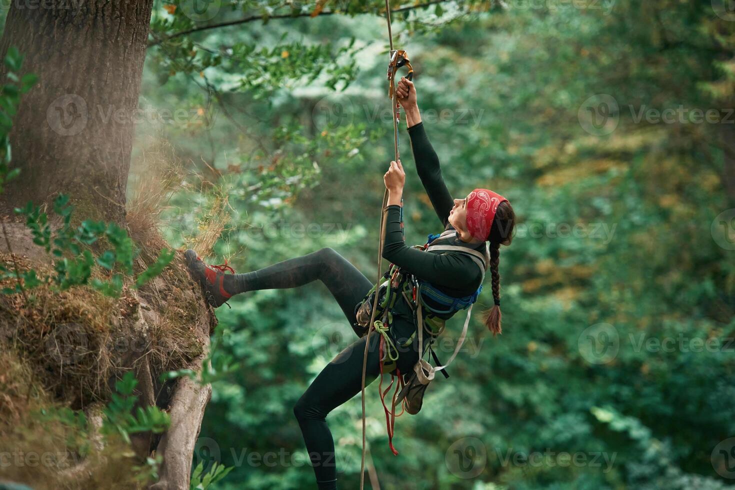 View from, the, side, hanging ,on, the rope. Woman is doing climbing in the forest by the use of safety equipment photo