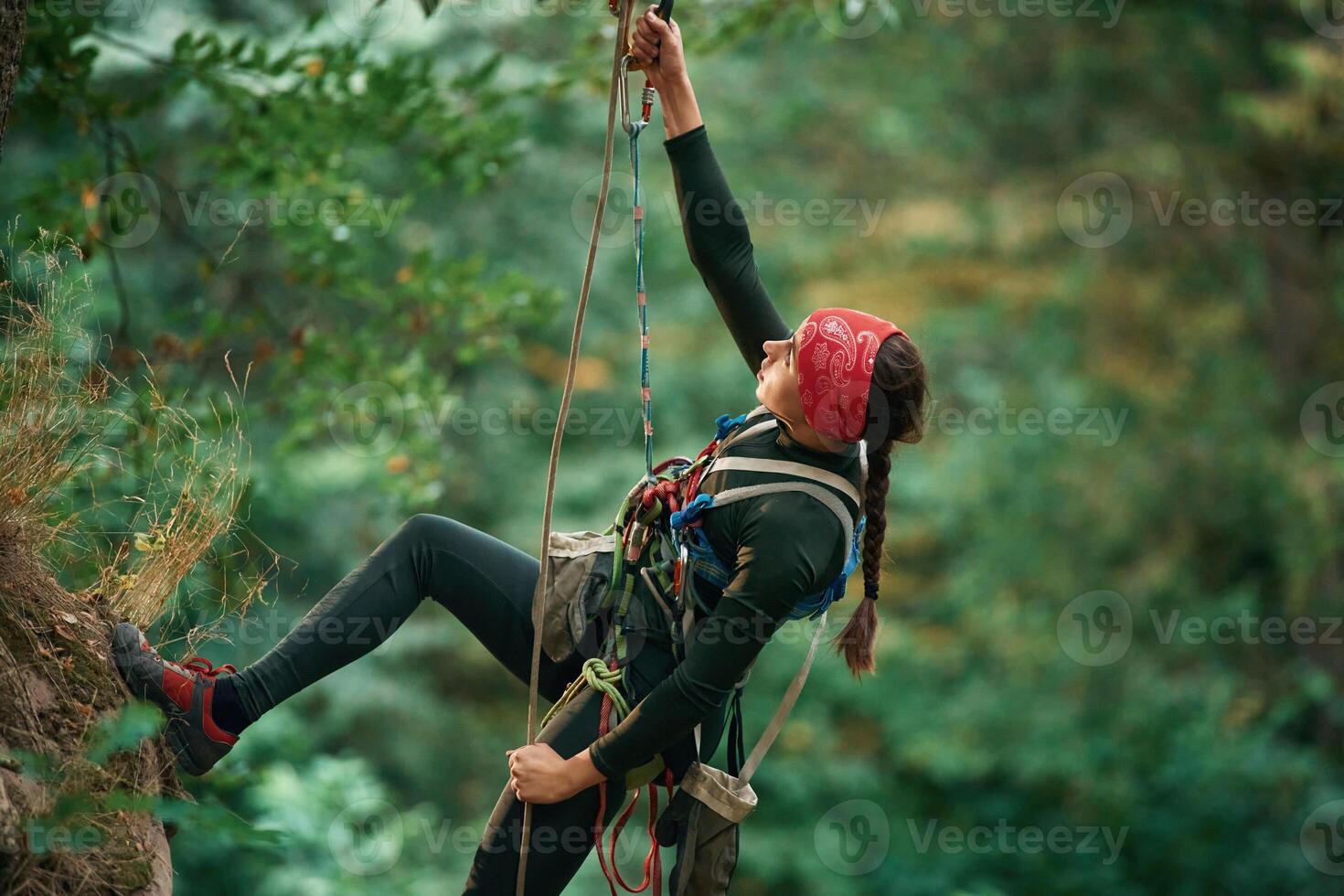 In s,portive, clothes, high up on the rope. Woman is doing climbing in the forest by the use of safety equipment photo