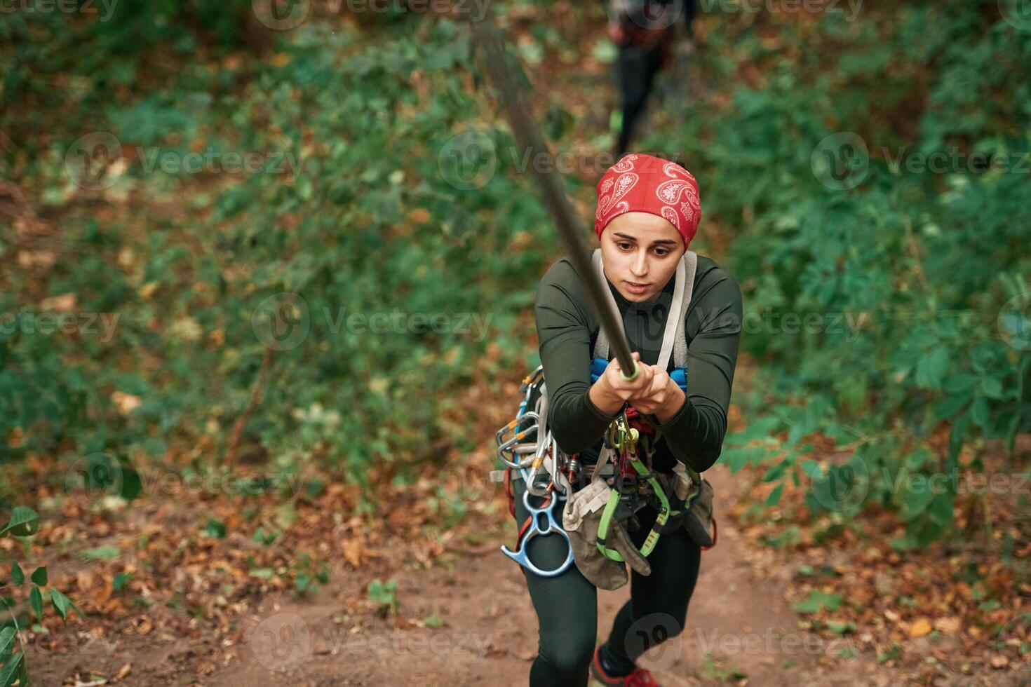 Front view. Woman, is doing climbing in the forest by the use of safety equipment photo