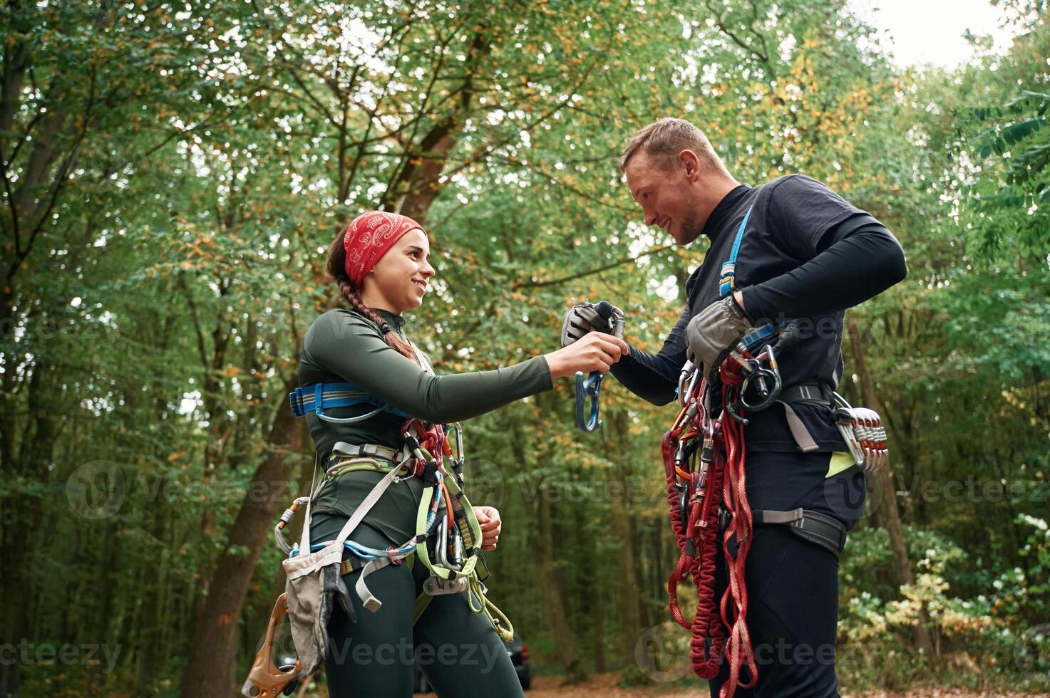 Standing together. Man and woman doing ,climbing in forest with use of safety equipment photo