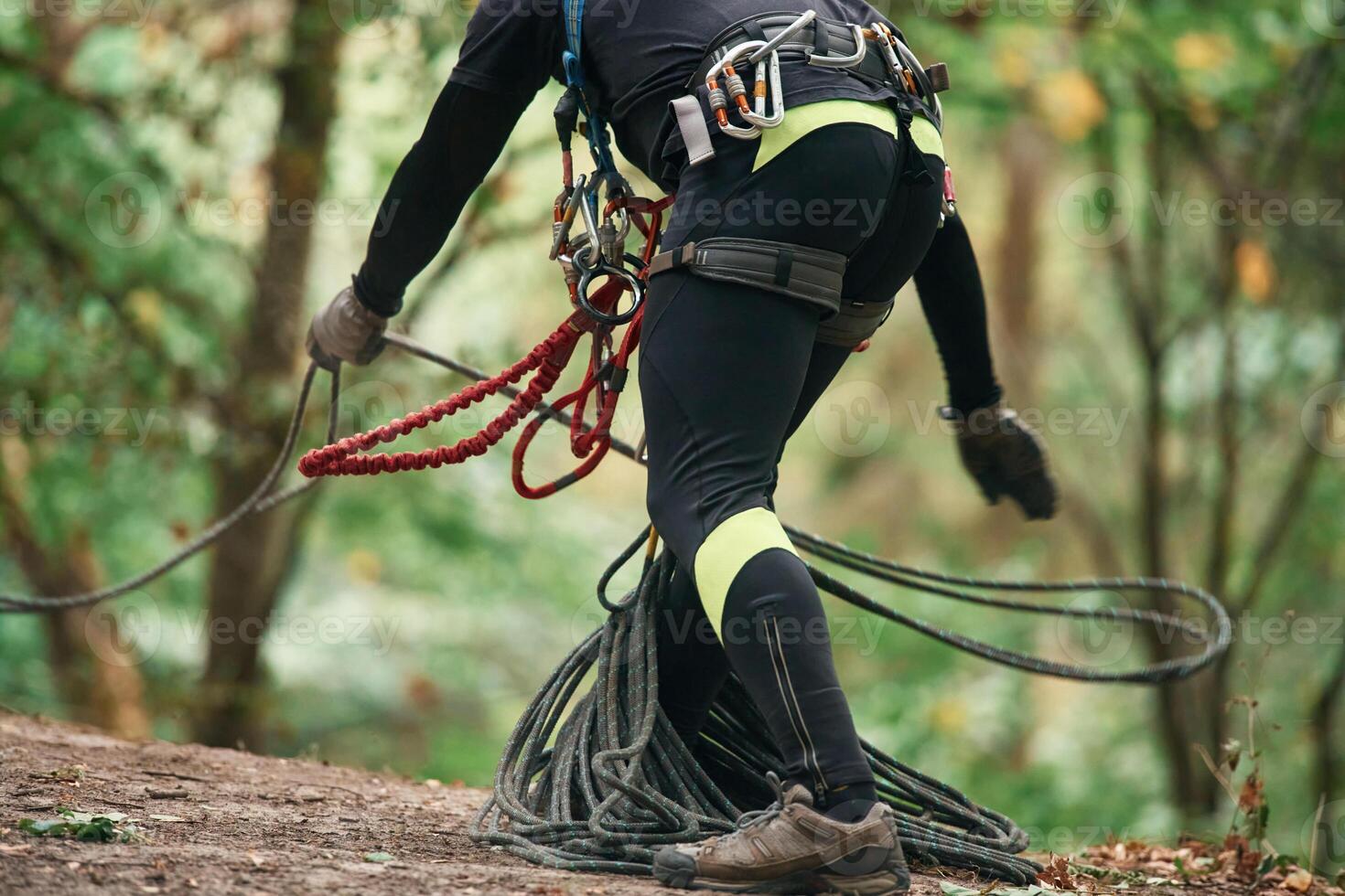 Close up, particle view. Man is doing climbing in the forest by use of safety equipment photo