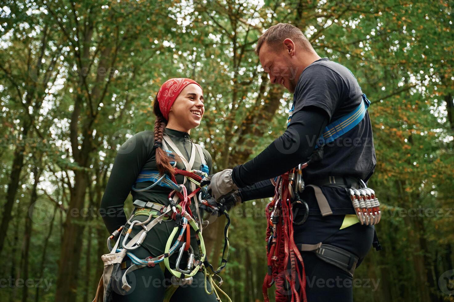 Standing, together. Man, and ,woman doing climbing in forest with use of safety equipment photo