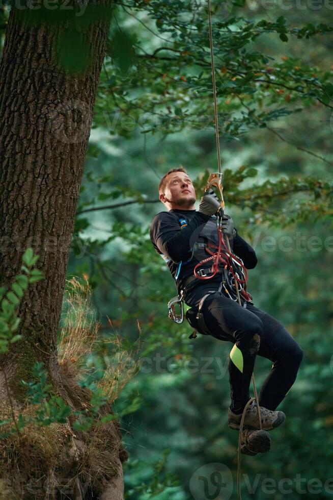 Activity, hanging on a rope. Man ,is, doing climbing in the forest by use of safety equipment photo