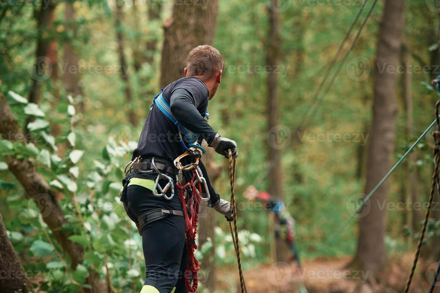 Process of preparing. Man ,is ,doing climbing in the forest by use of safety equipment photo