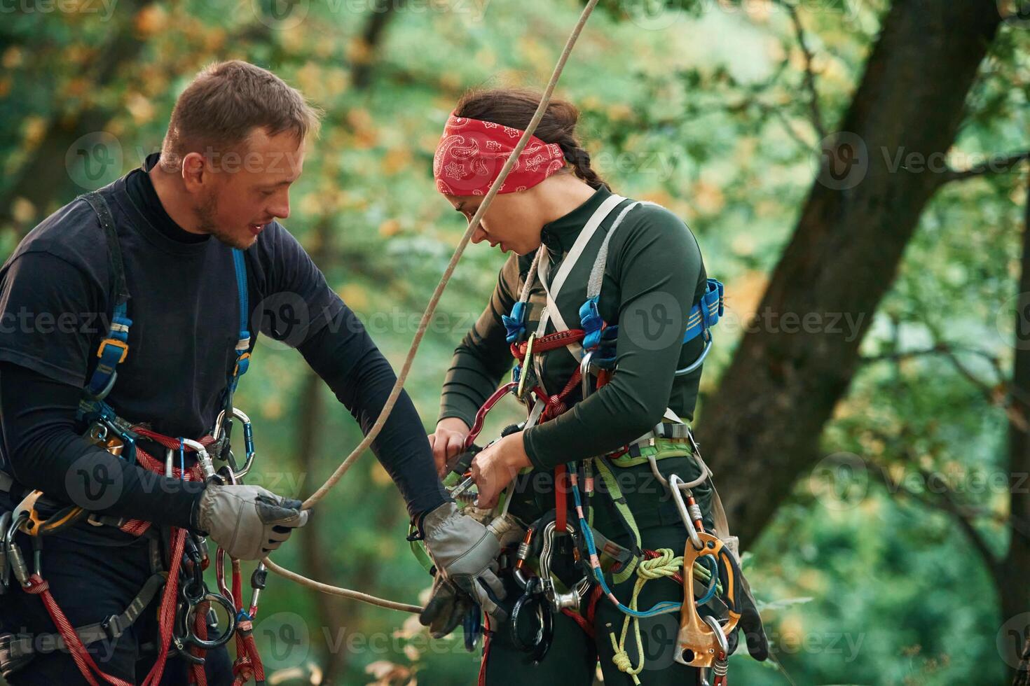 Man, is, helping the woman. Doing climbing in forest with use of safety equipment photo