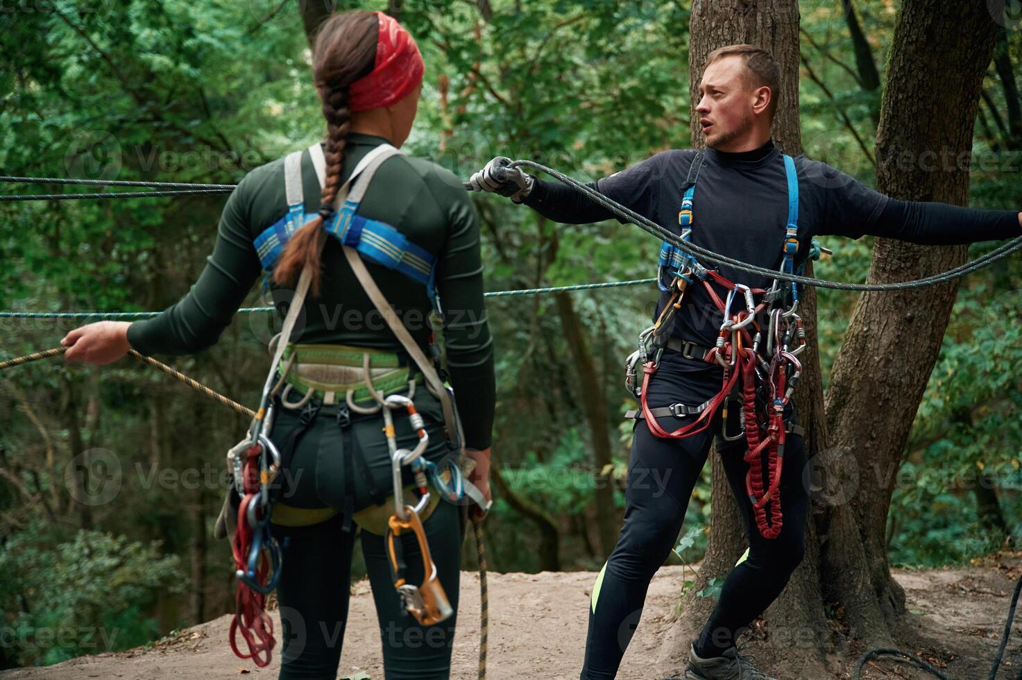 In the forest... Man and woman doing climbing with use of safety equipment photo