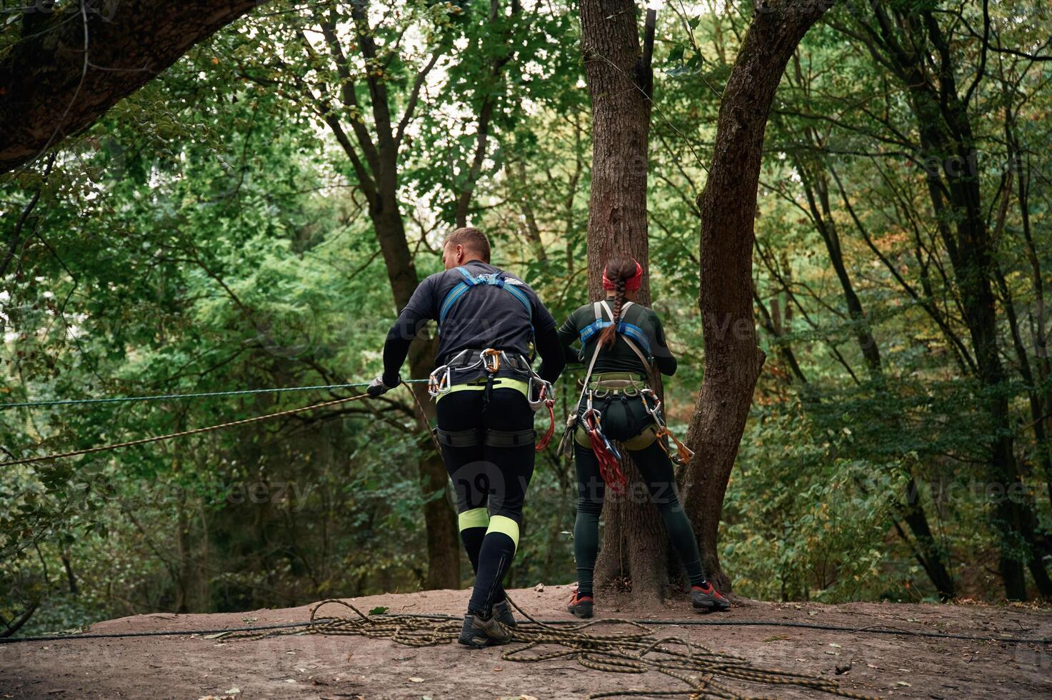 In the forest.. Man and woman doing climbing with use of safety equipment photo