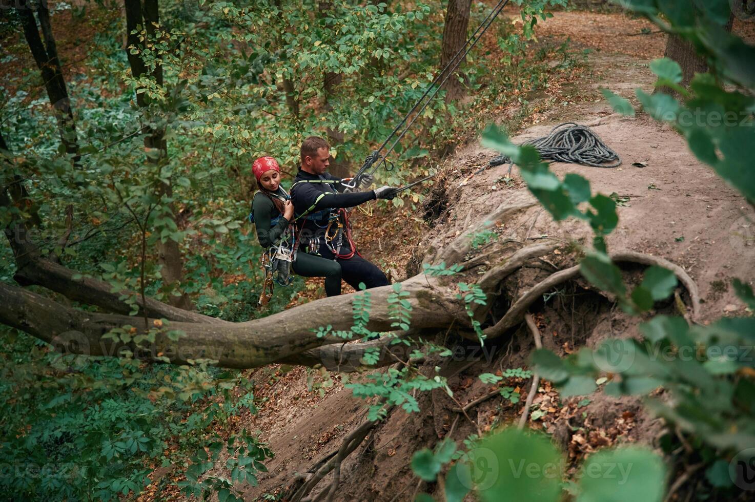 Going, down. Man and woman doing climbing in forest with use of safety equipment photo