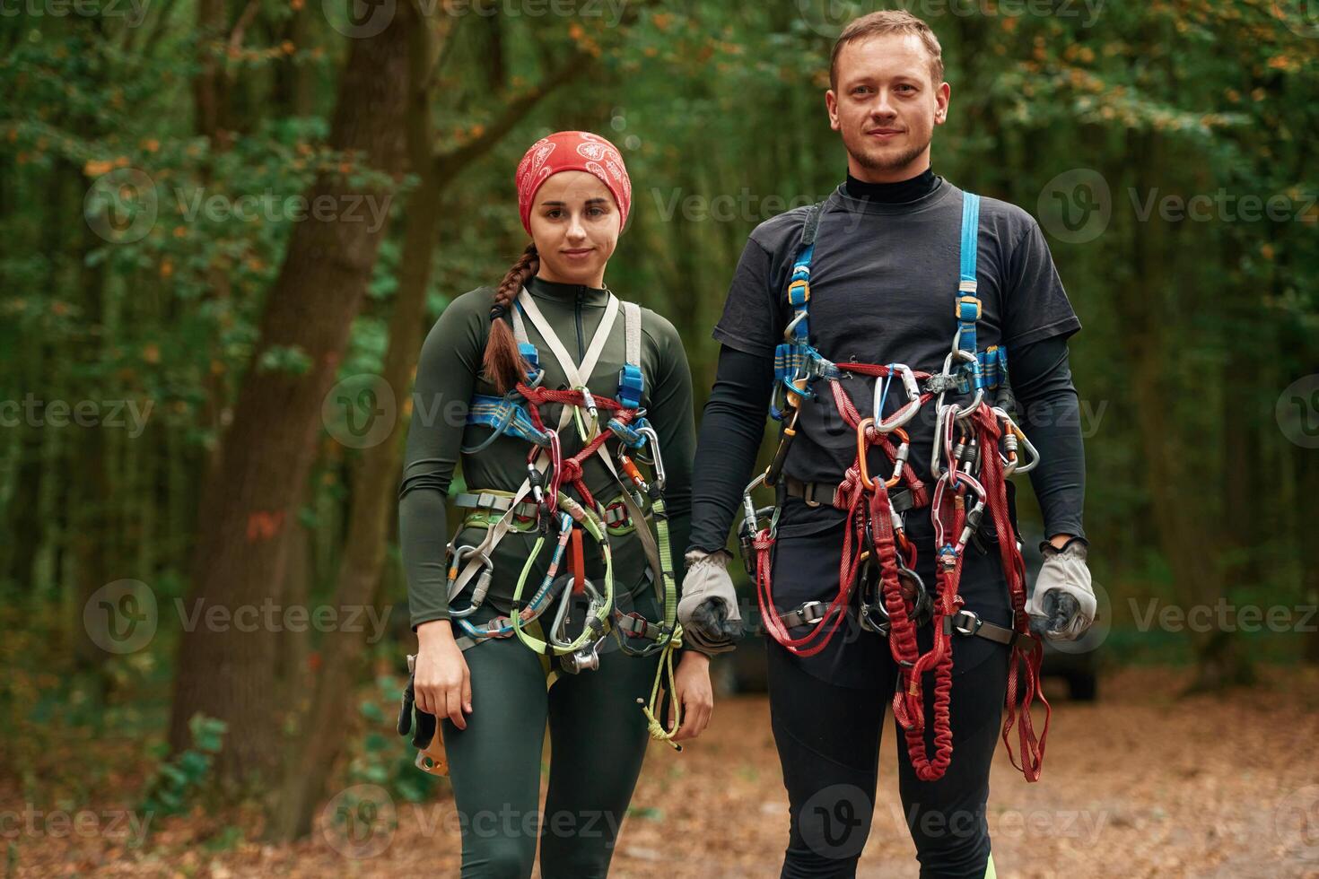 Standing, and posing. Man and woman doing climbing in forest with use of safety equipment photo