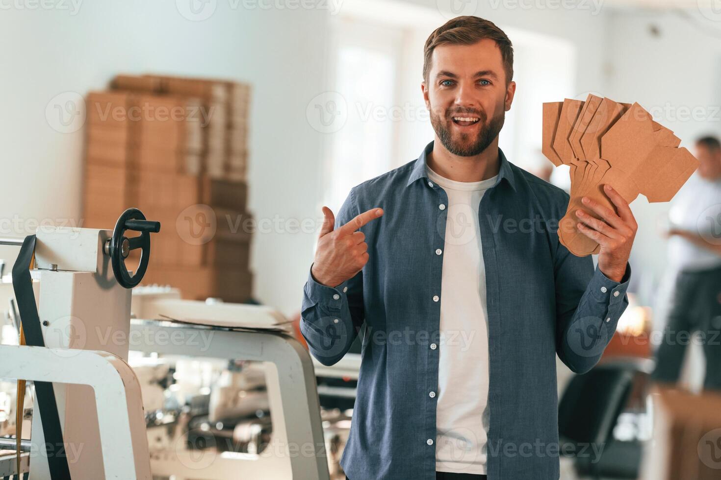 With ,cardboards. Handsome ,man ,is working at the factory of creating eco boxes photo