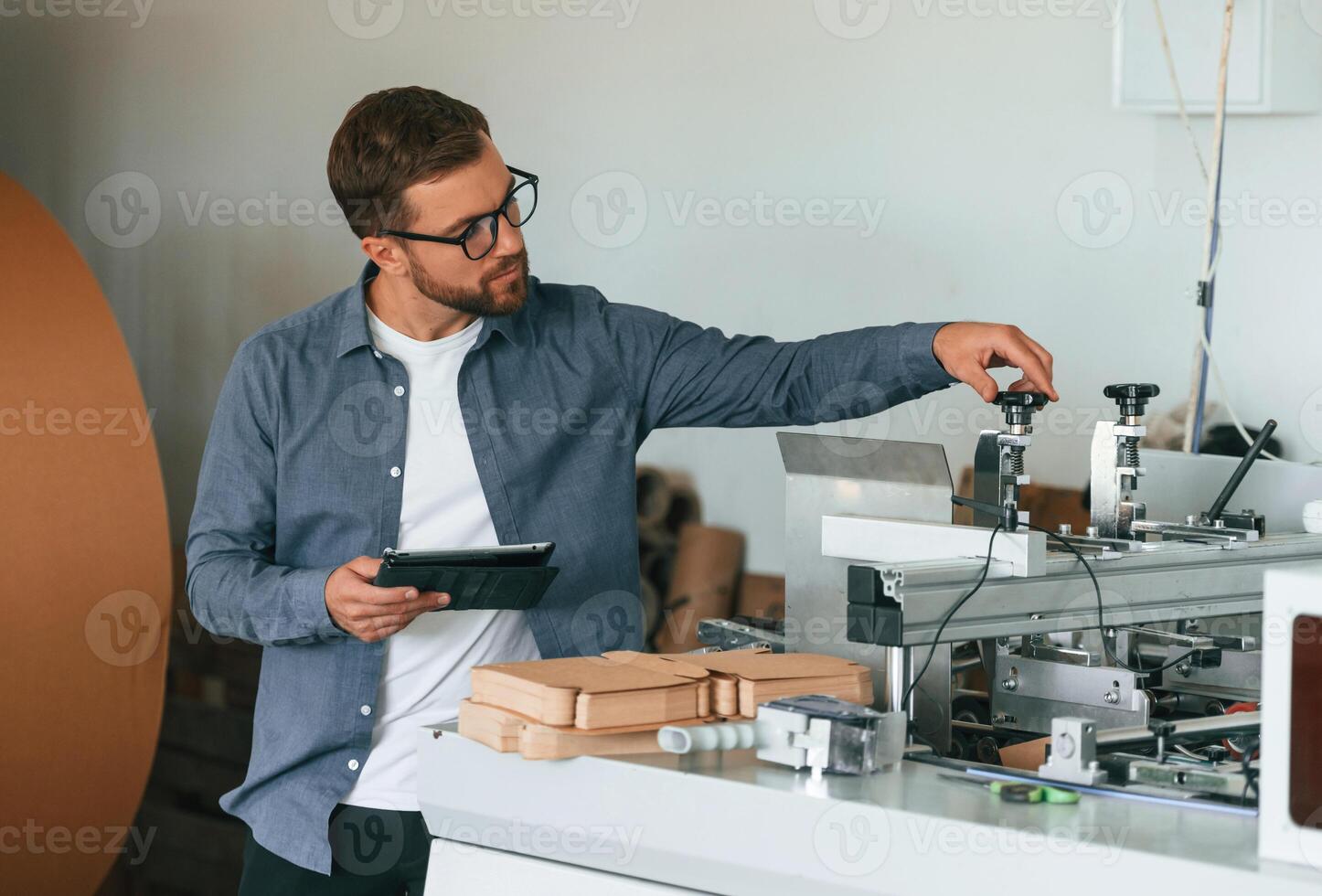 Front,, view. Handsome man is working at the factory of creating eco boxes photo