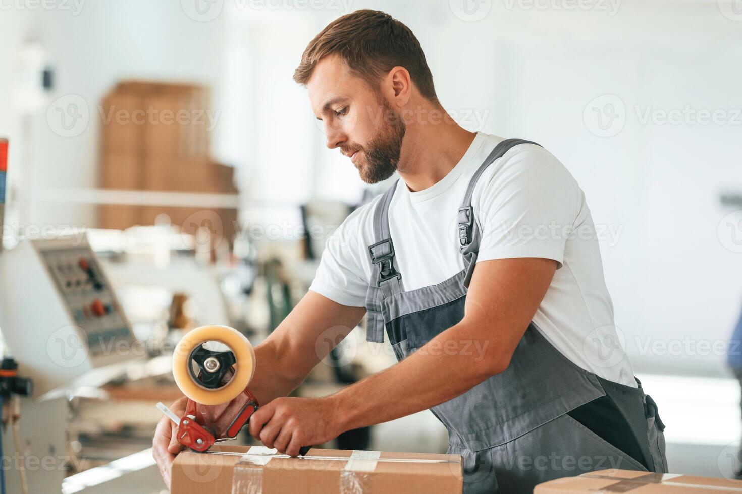 In grey uniform.., Handsome man is working at the factory of creating eco boxes photo