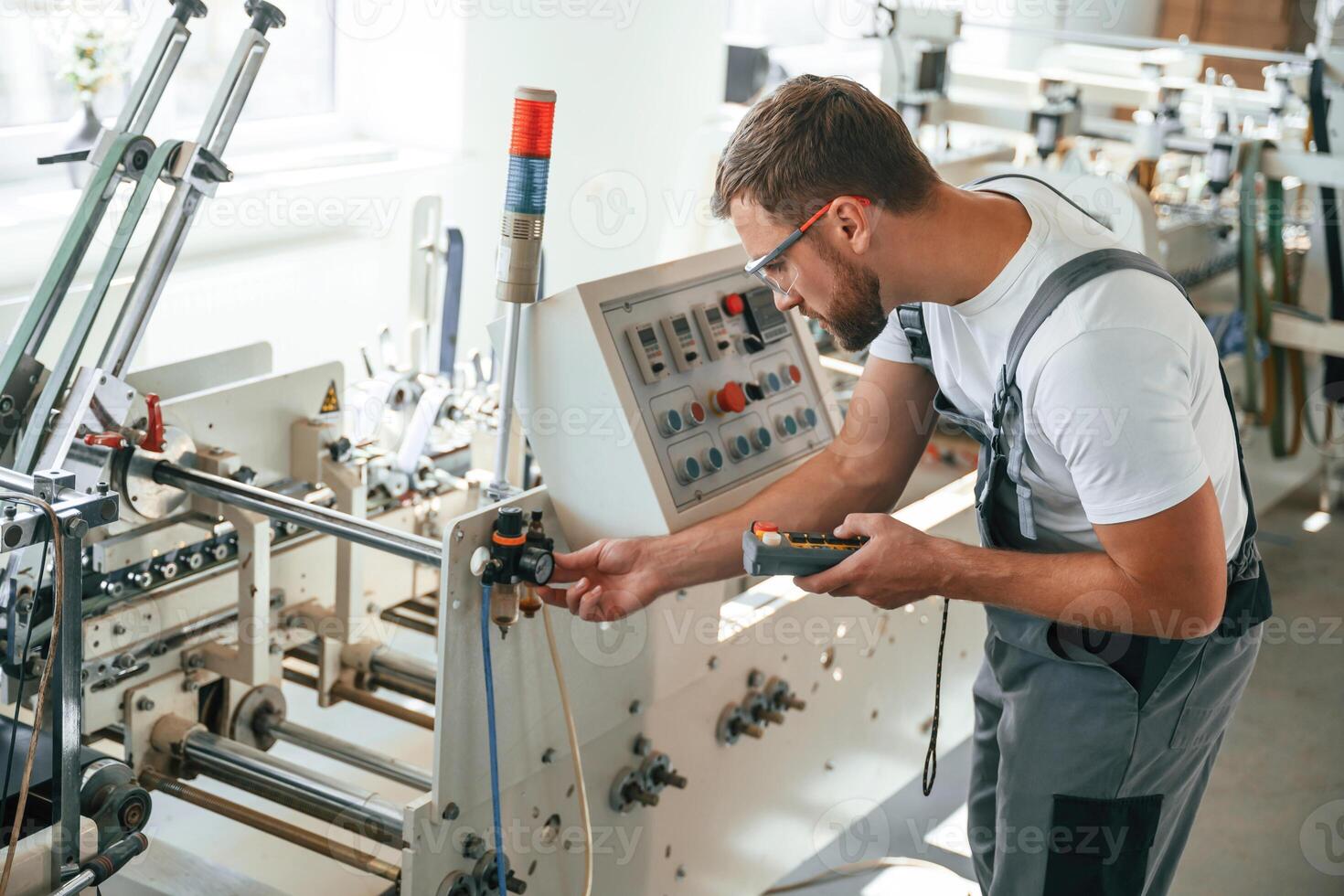 Standing by,, the machine. Handsome man is working at the factory of creating eco boxes photo