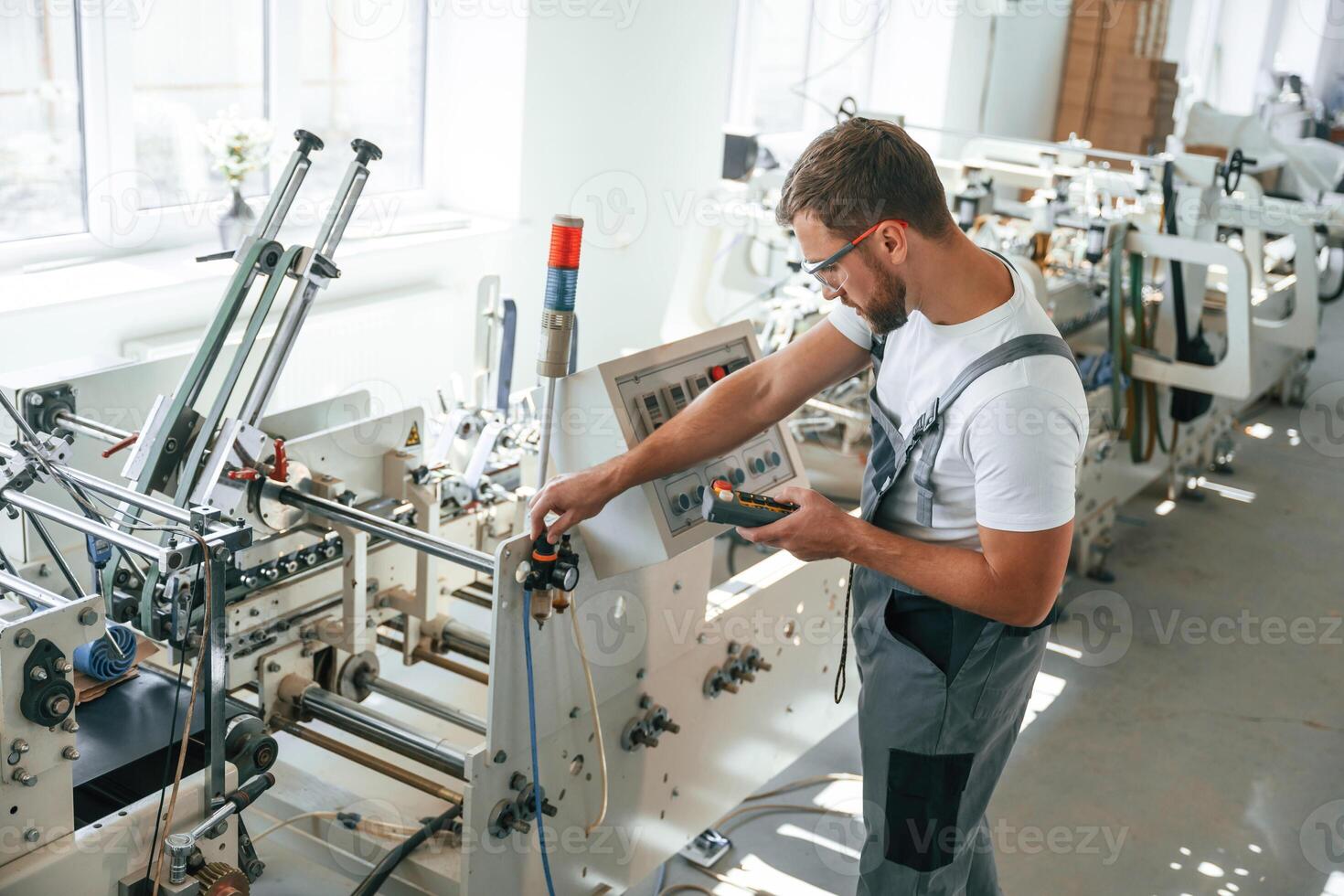 Standing by, the machine. Handsome man is working at the factory of creating eco boxes photo