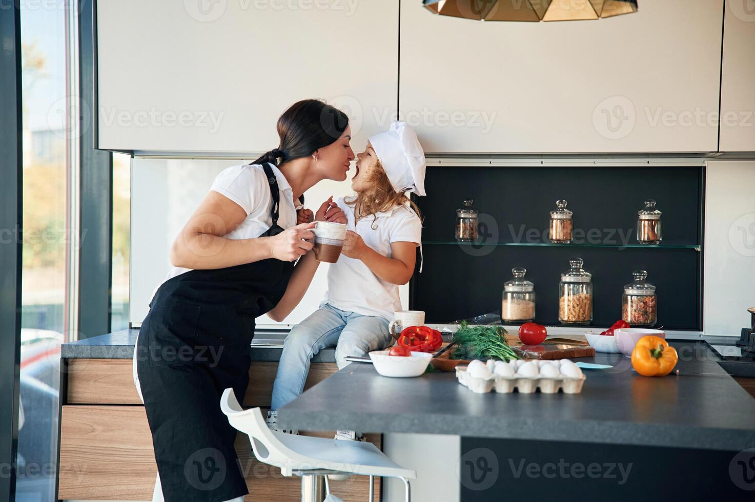 Playful ,mood. Mother with her daughter are preparing food on the kitchen photo