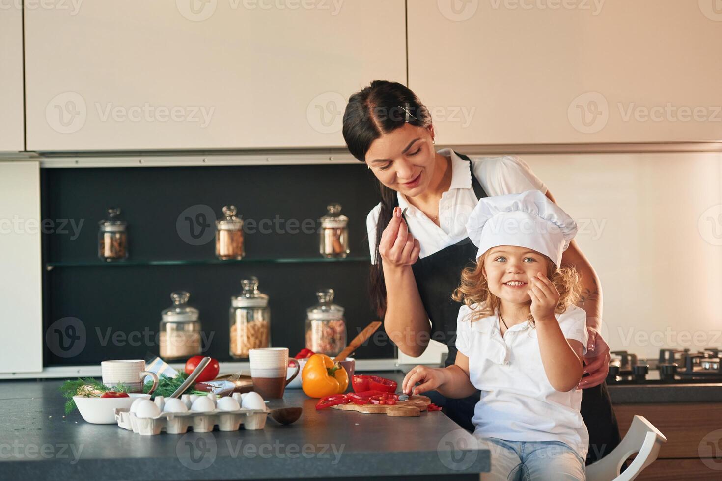 Eating pepper. Mother with he,r daughter, are preparing food on the kitchen photo