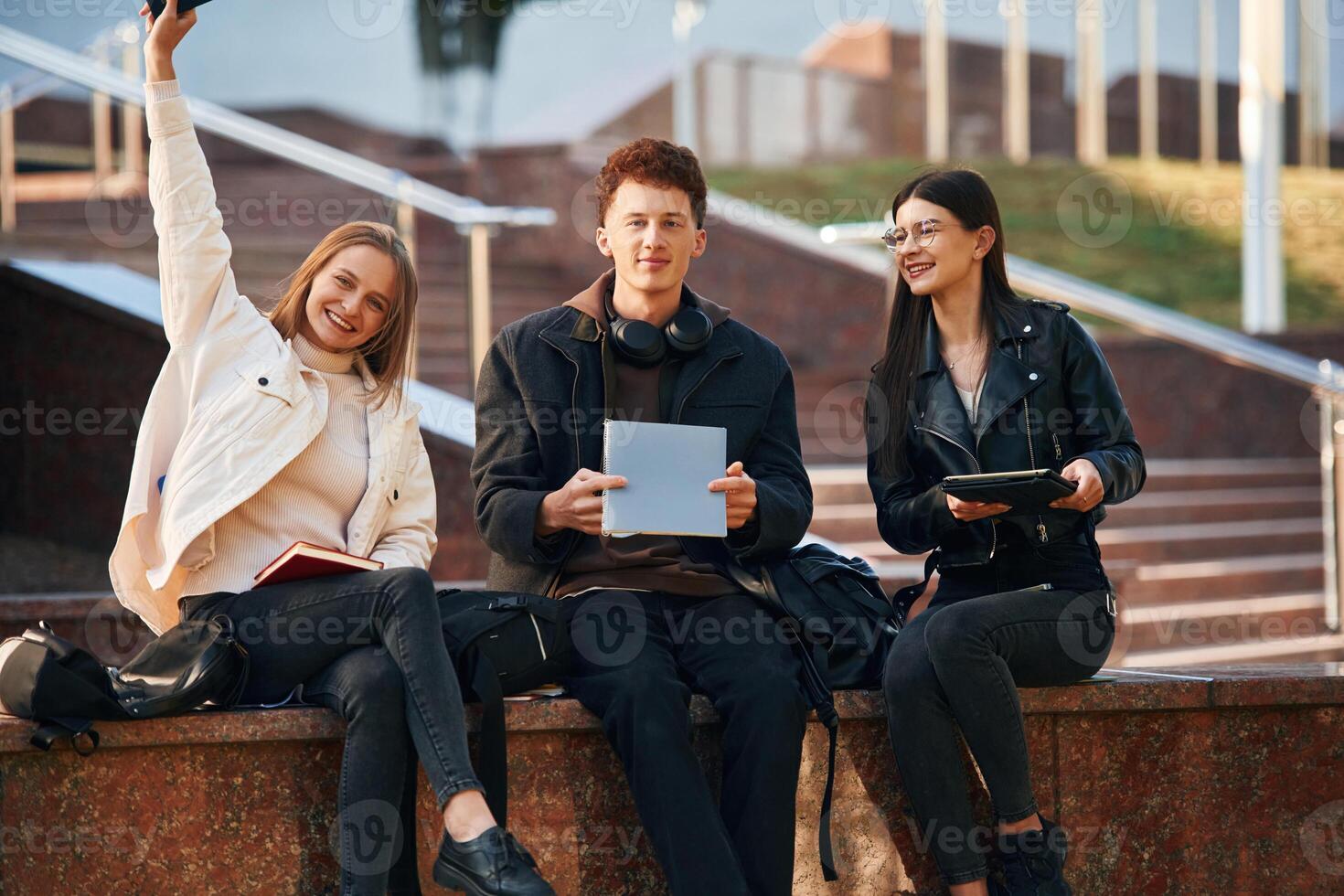 With ,notepad. Three young students are outside the university outdoors photo