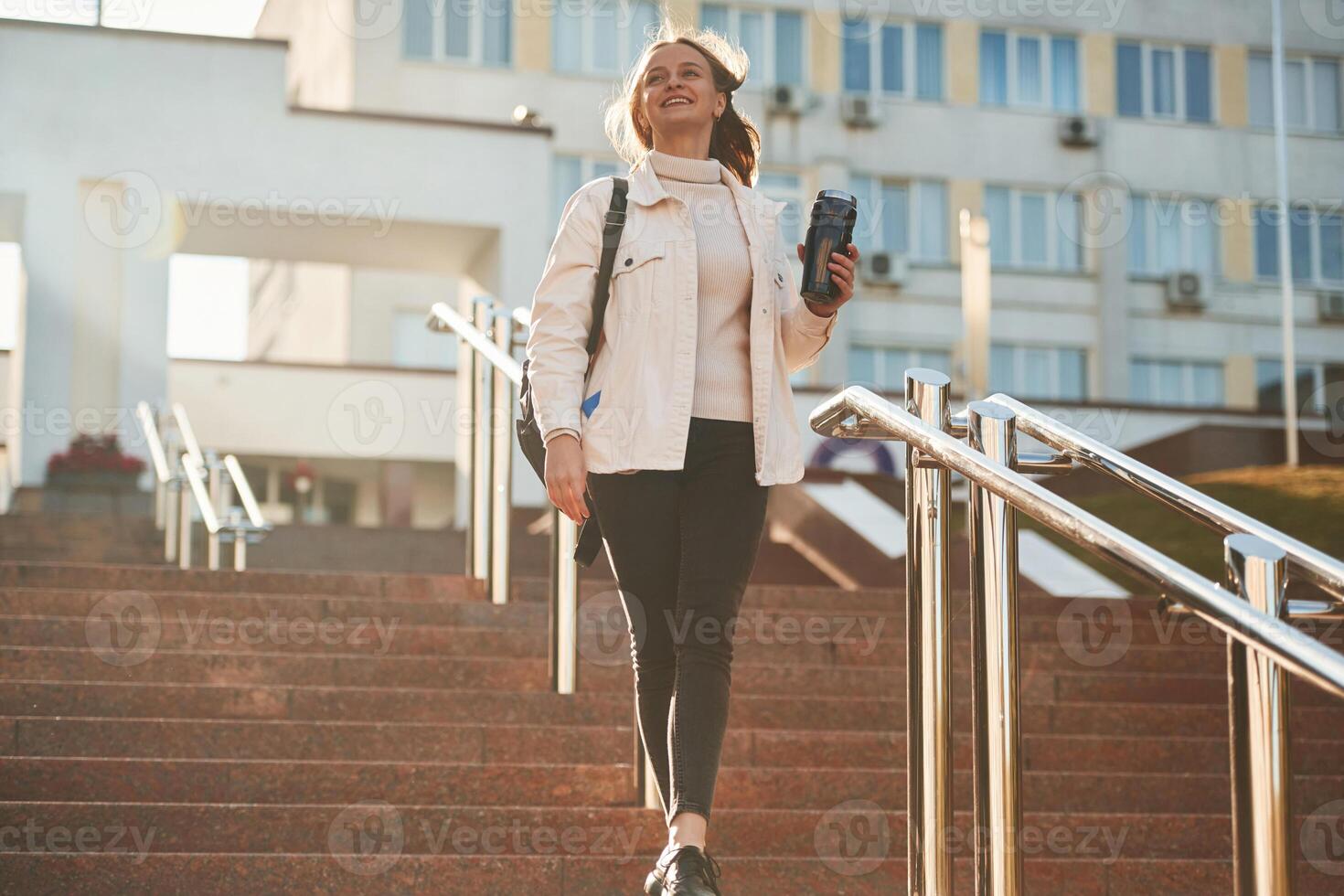 With water bottle.. Young, female student in casual clothes is outdoors photo