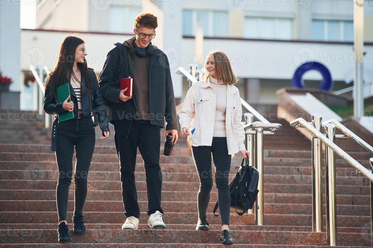 Going by the stairs.. Three young students are outside the university outdoors photo