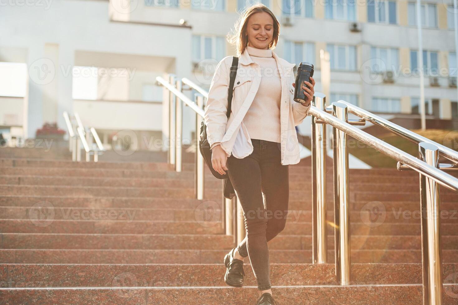 With water, bottle. Young female student in casual clothes is outdoors photo