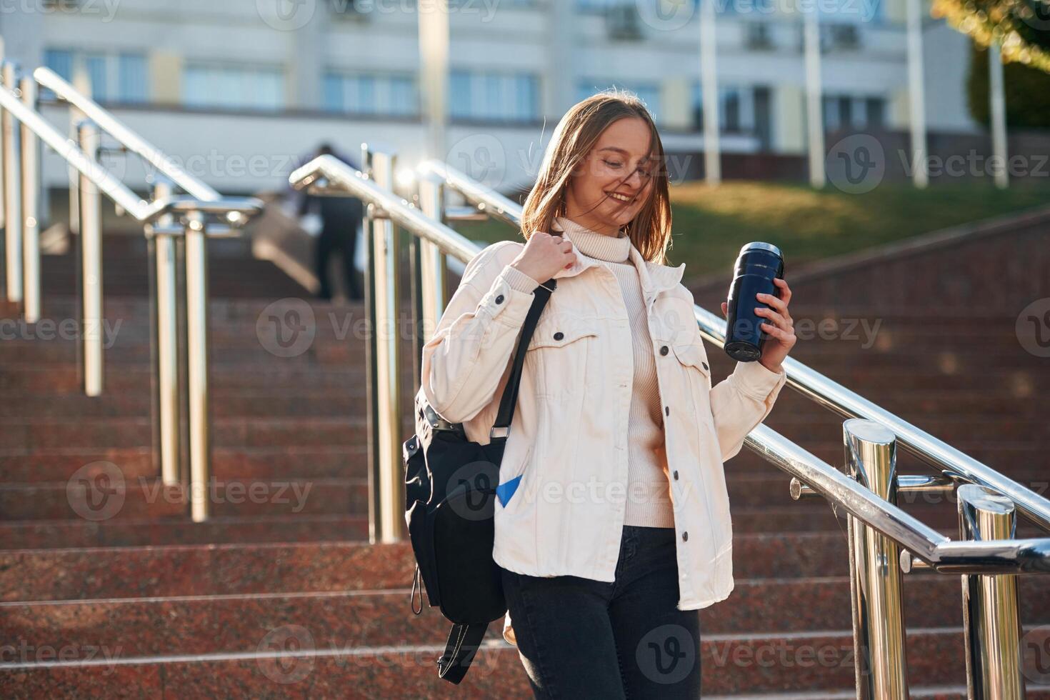 With ,water bottle. Young female student in casual clothes is outdoors photo