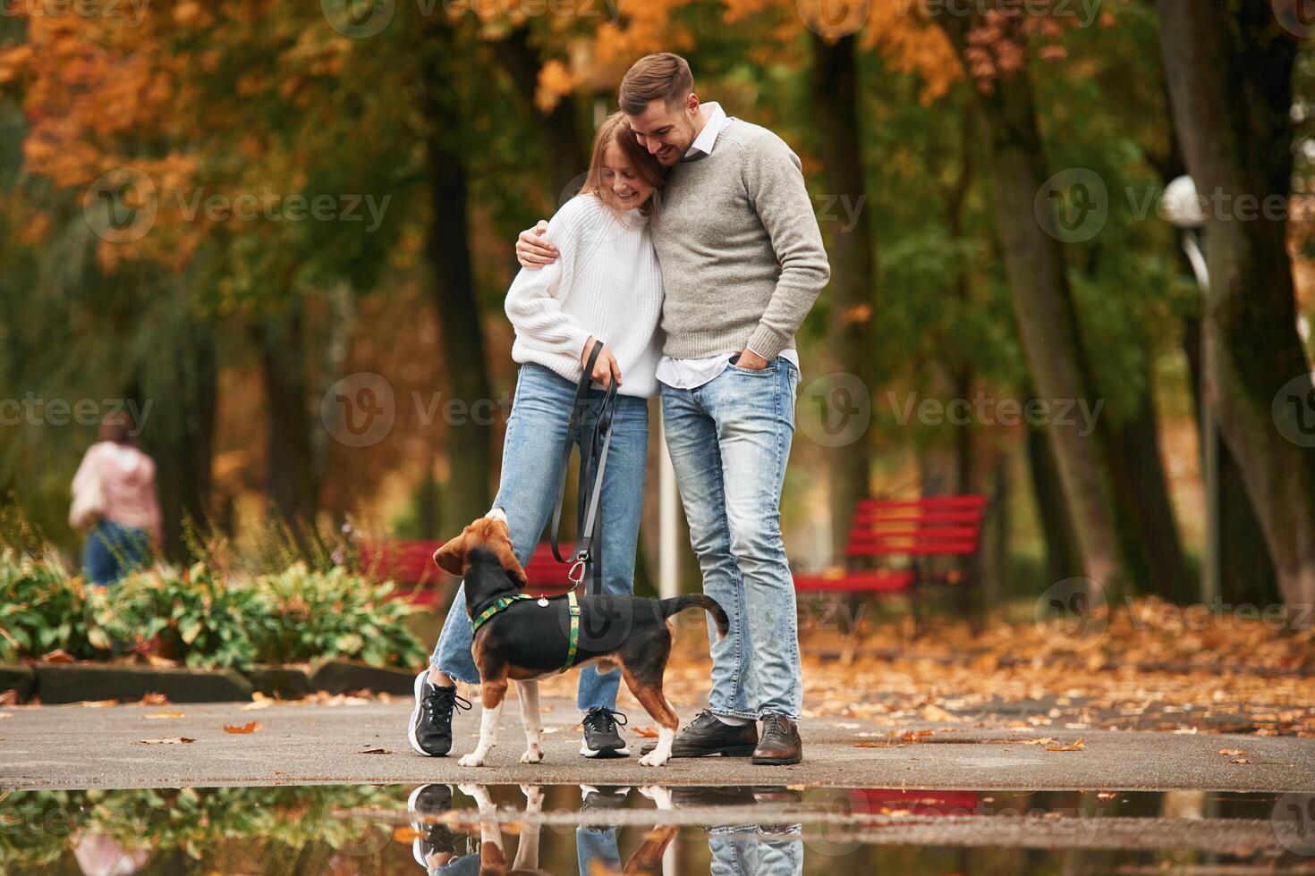 Autumn season walk. Lovely couple are with their cute dog outdoors photo