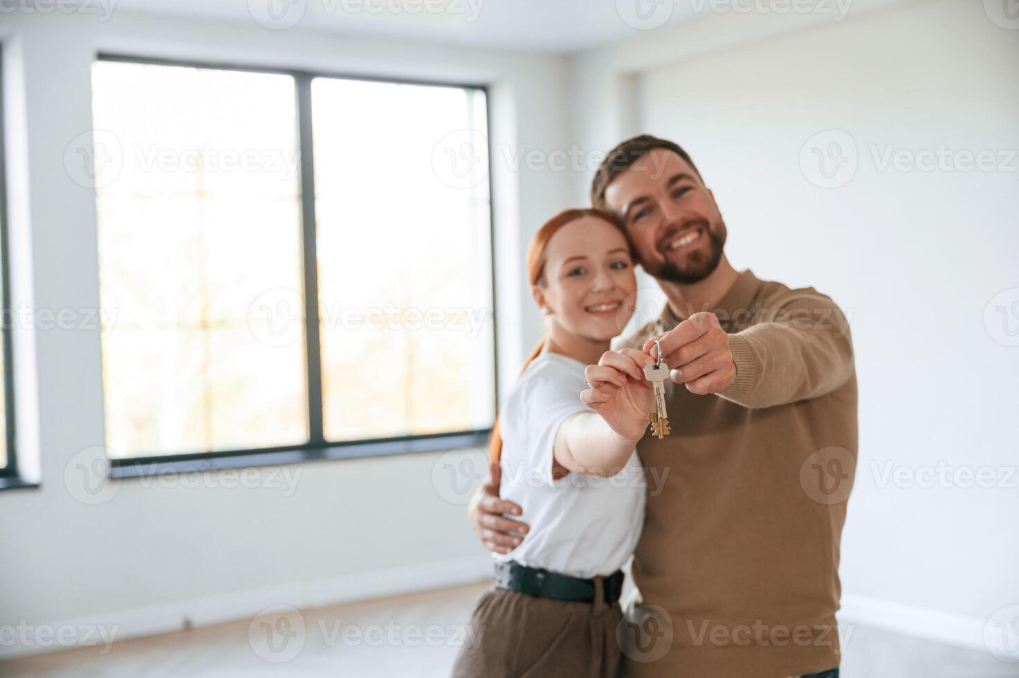 Happy ,couple as new owners of, the house holding the keys in hands photo