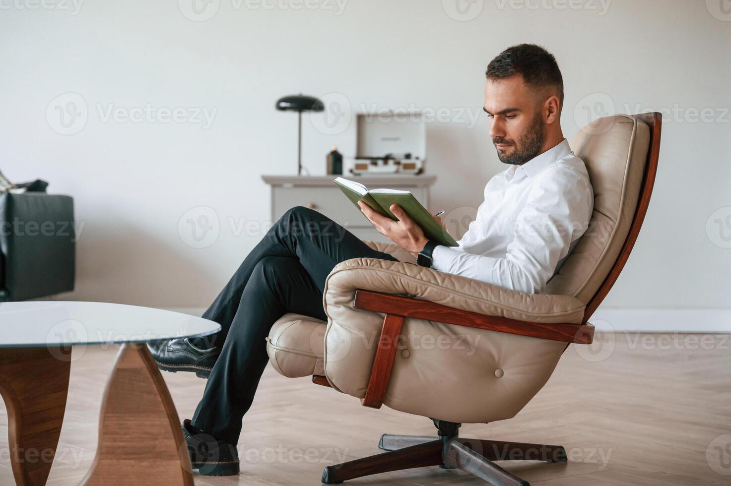Elegant man in formal clothes is sitting, indoors at his cabinet photo