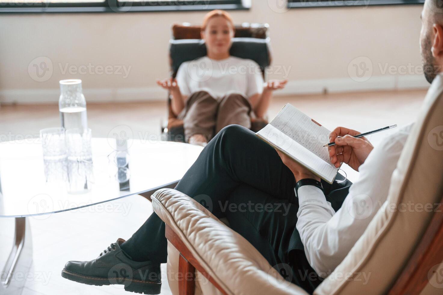Woman is sitting in chair,, at an appointment with a psychologist photo