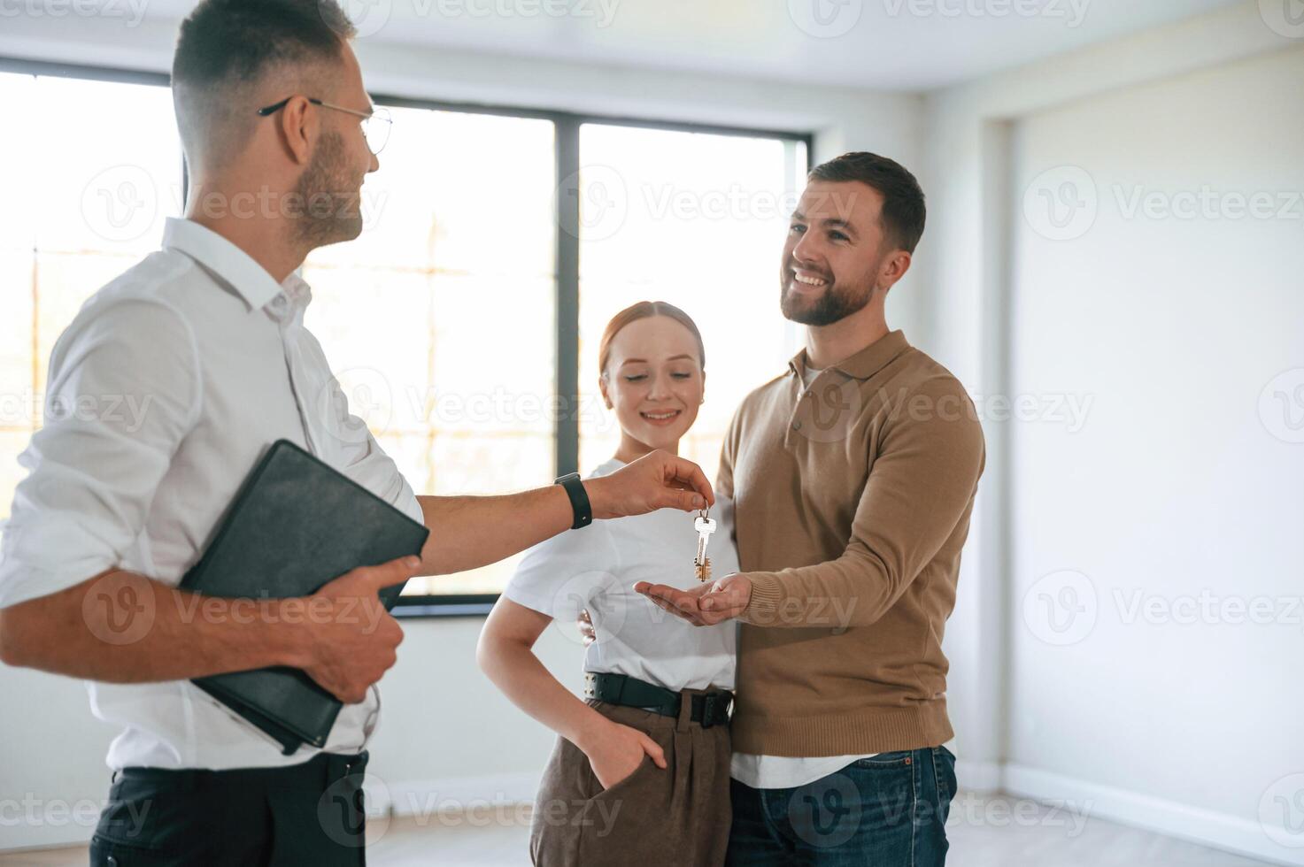 Happy new owners, taking keys. Realtor shows an apartment to a young couple photo