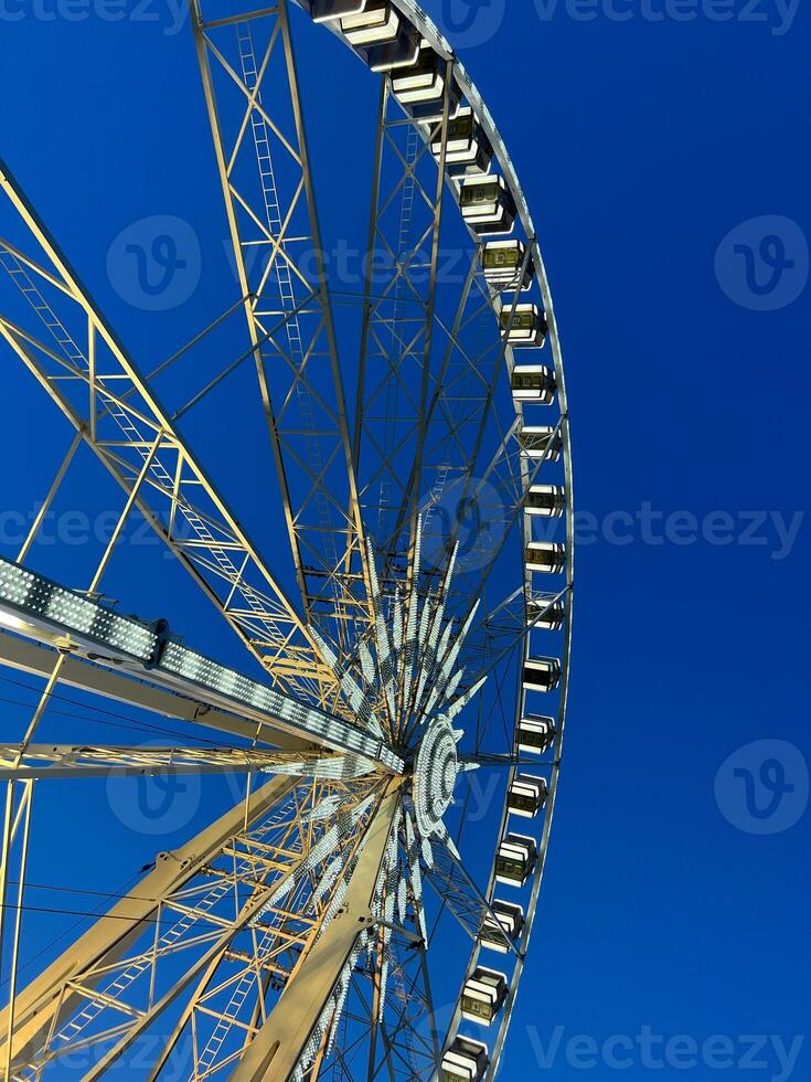 A beautiful golden Ferris wheel stands out against a clear blue sky, photo