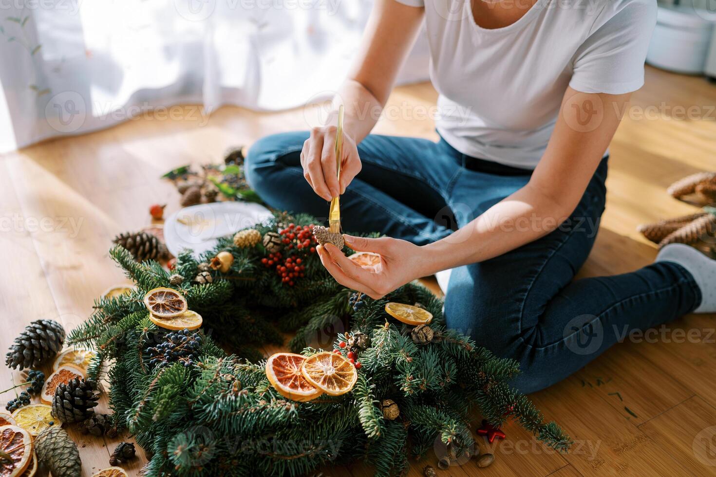 Decorator paints a pine cone for the New Year wreath with a brush. Cropped photo
