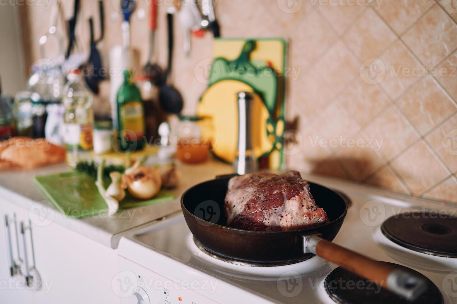Raw roast beef is fried in a pan on the stove in the kitchen photo